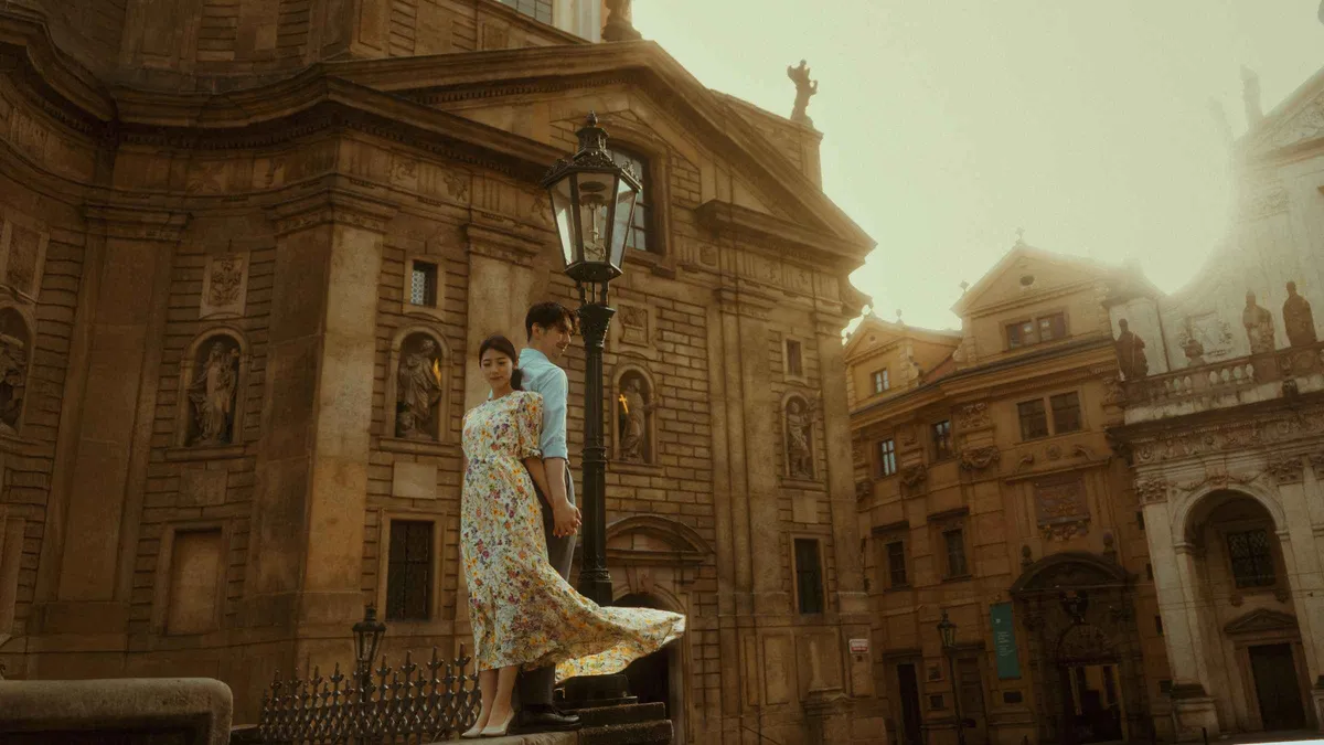 A photographer framing a couple by the Rudolfinum during a cinematic Prague photoshoot, Prague