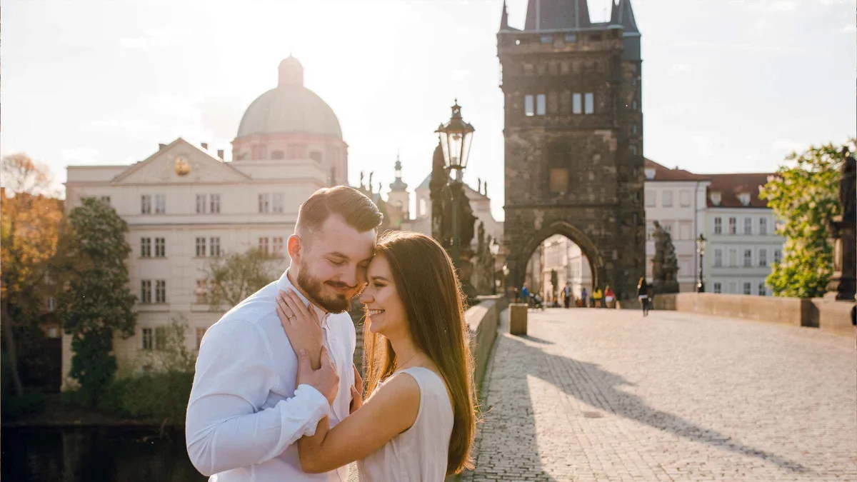 A photographer shooting a couple among the baroque statues on Charles Bridge during a Prague photoshoot, Prague
